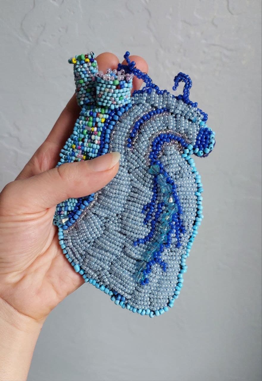 Corazón de abalorios grises y azules sostenido en una mano