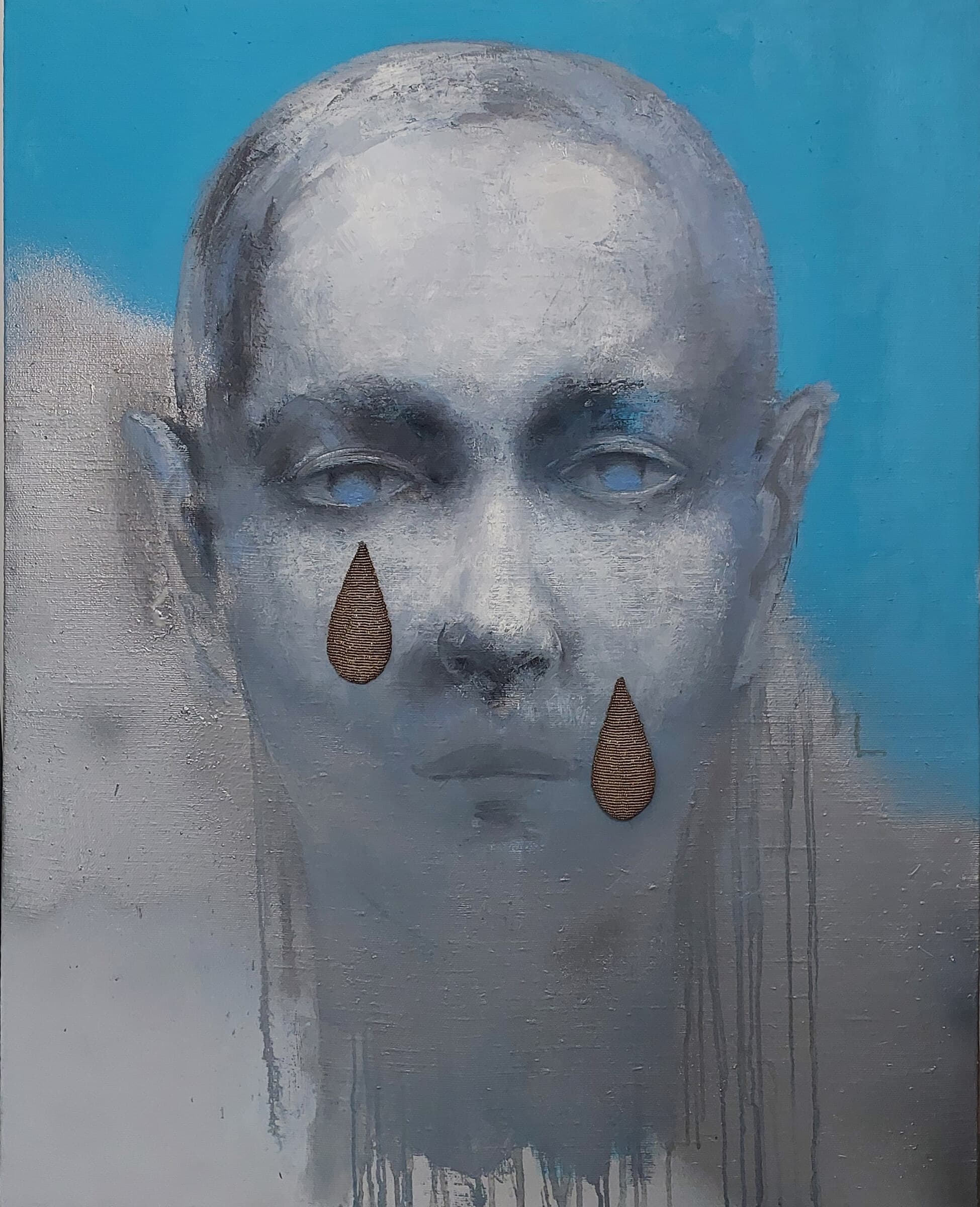 Rostro gris sobre fondo azul, con dos lágrimas bordadas en relieve